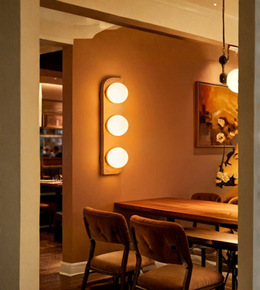 Dining room with wooden table and chairs, wall-mounted light fixture, and framed picture on the wall.