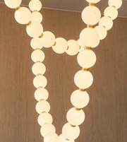 Chandelier with round glass bulbs and gold accents on a beige background