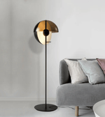 Modern sculptural floor lamp with smoked glass shade beside sofa