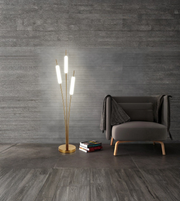 Modern brass floor lamp with frosted tube lights beside armchair