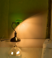 Vintage green banker lamp casting warm light on desk surface