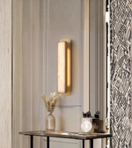 Vertical modern wall sconce with warm ambient glow on paneled wall