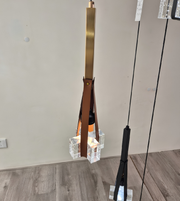Modern pendant light fixture with a brown leather strap and glass elements on a neutral background.