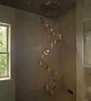 Chandelier with gold circular design hanging in a room with a window and door.