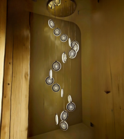 Chandelier with circular lights hanging from a ceiling in a room with wooden walls.