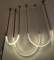 Modern ceiling light fixture with curved LED lights on a neutral background