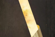 Modern marble wall sconce with brass spiral accent glowing warmly