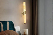 Designer wall sconce with warm lighting beside a bedroom setup