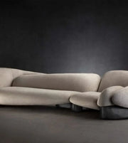 Modern beige sectional sofa with sculptural design against a dark background
