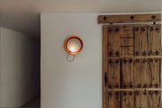 Minimalist wall-mounted light installed in hallway near wooden door