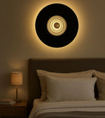 Modern circular wall light above bed in cozy bedroom with neutral decor