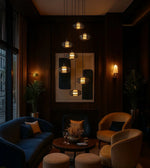 Modern pendant lighting over elegant lounge with velvet armchairs, wall art, and decor