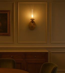 Modern brass wall sconce glowing in elegant dining room with wood cabinet and paneling