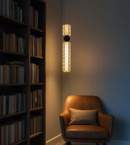 Modern pendant light above brown leather armchair in cozy reading nook with bookshelf