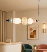 Modern pendant light with colored glass shades in stylish living room with decor and furniture