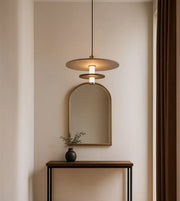 Modern pendant light over console table with arch mirror and minimalist decor in neutral room